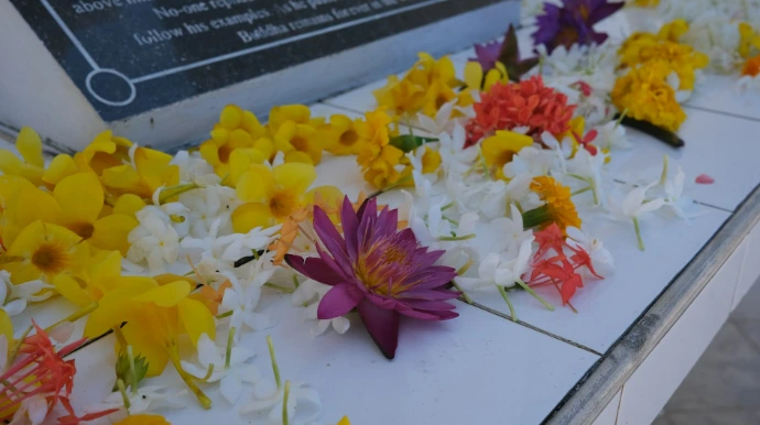 Colorful flower garlands adorn a memorial plaque.